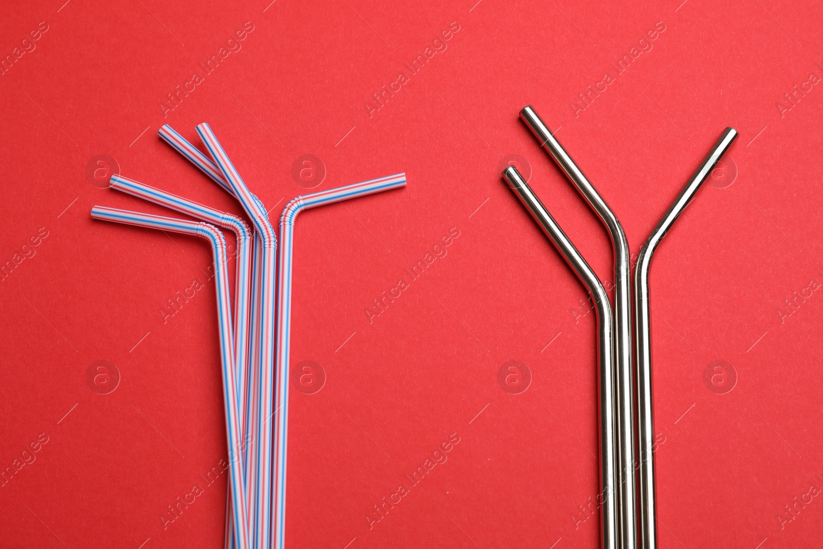 Photo of Plastic and metal drinking straws on red background, top view