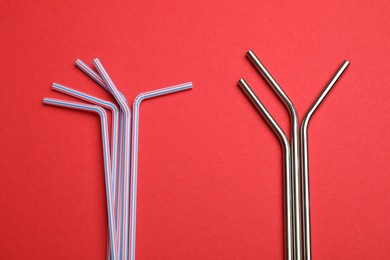 Photo of Plastic and metal drinking straws on red background, top view