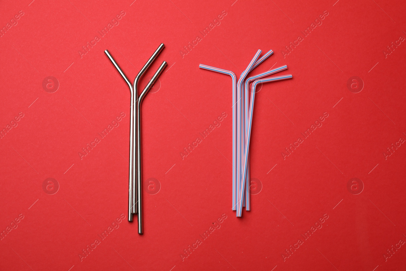 Photo of Plastic and metal drinking straws on red background, top view