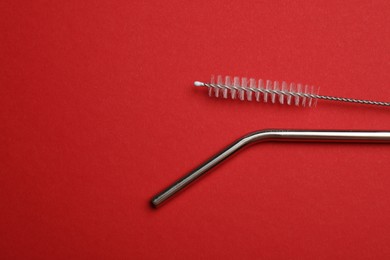 Photo of Metal drinking straw and cleaning brush on red background, top view