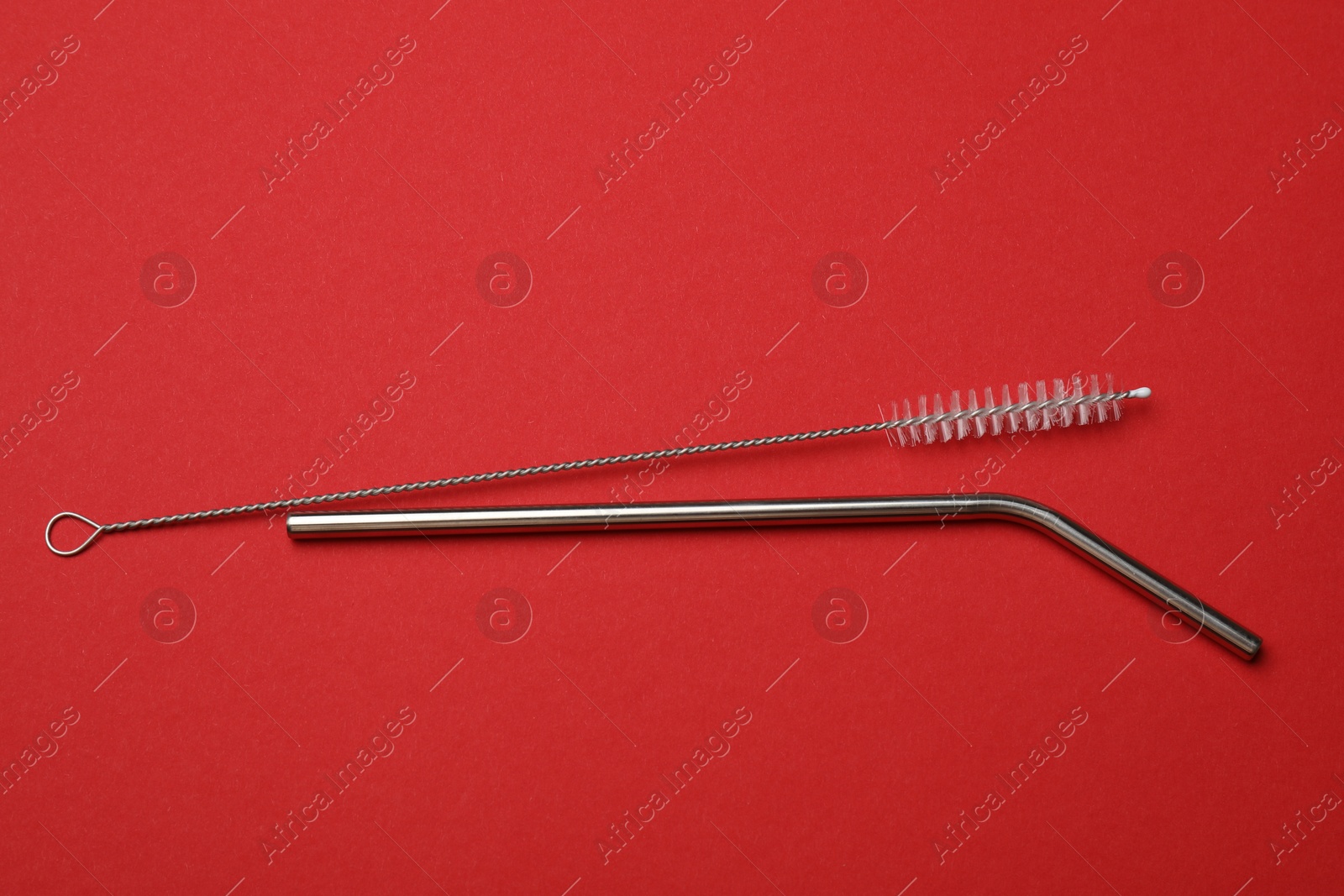 Photo of Metal drinking straw and cleaning brush on red background, top view