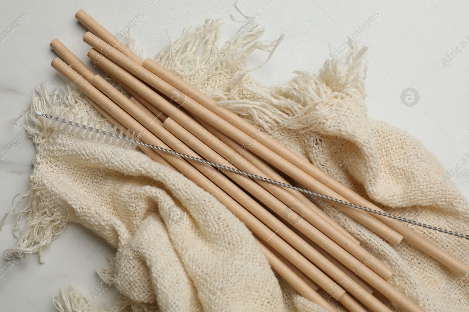 Photo of Bamboo drinking straws and cleaning brush on marble table, top view