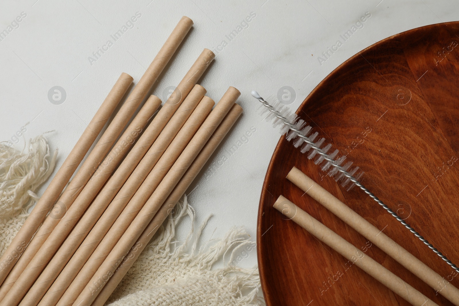 Photo of Bamboo drinking straws and cleaning brush on marble table, top view