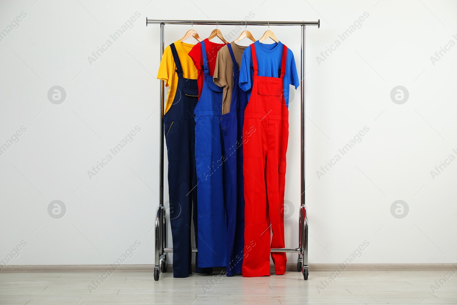 Photo of Workers' uniforms on clothing rack near grey wall indoors