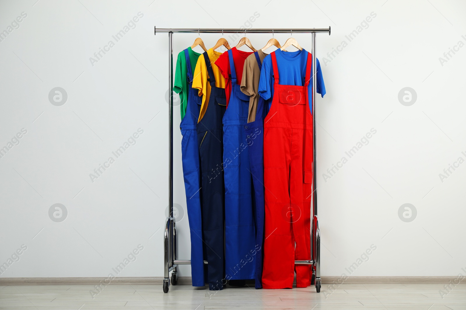 Photo of Workers' uniforms on clothing rack near grey wall indoors