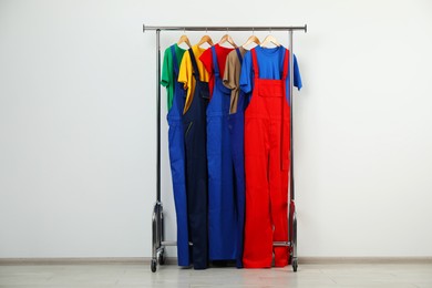 Photo of Workers' uniforms on clothing rack near grey wall indoors