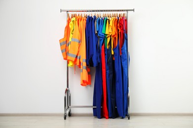 Photo of Workers' uniforms on clothing rack near grey wall indoors