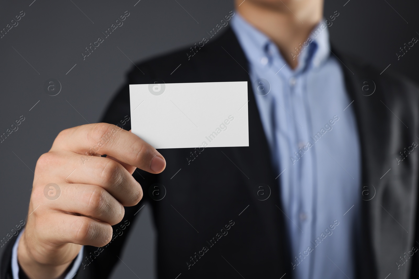 Photo of Man holding blank business card on grey background, closeup. Mockup for design