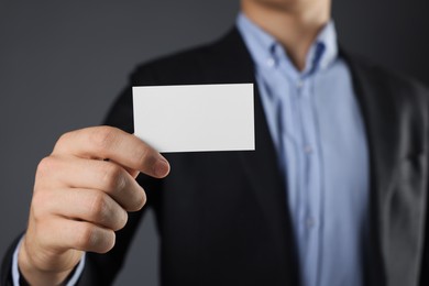 Photo of Man holding blank business card on grey background, closeup. Mockup for design