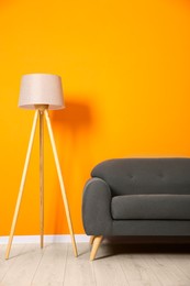 Stylish sofa and lamp near orange wall indoors