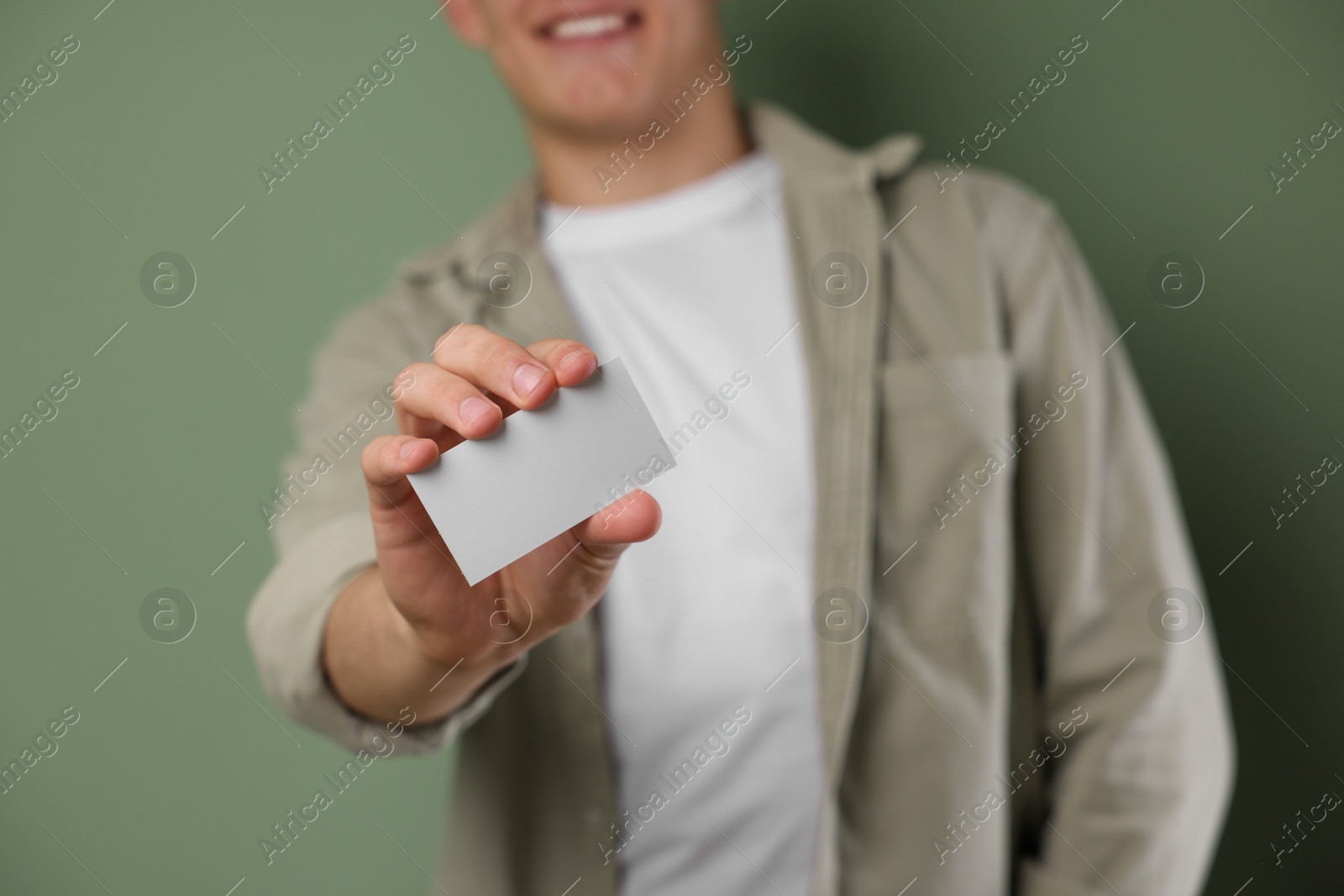 Photo of Man holding blank business card on green background, closeup. Mockup for design