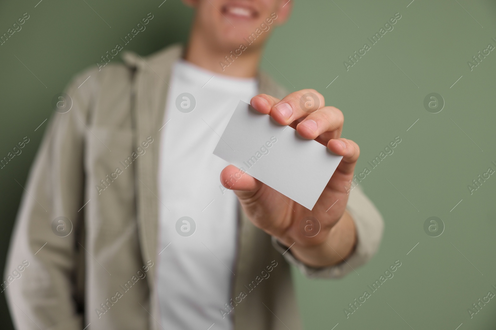 Photo of Man holding blank business card on green background, closeup. Mockup for design