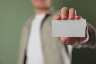 Photo of Man holding blank business card on green background, closeup. Mockup for design