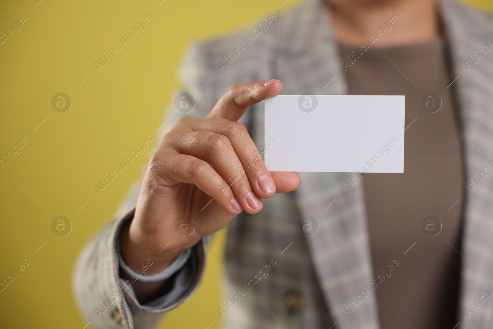 Photo of Woman holding blank business card on yellow background, closeup. Mockup for design