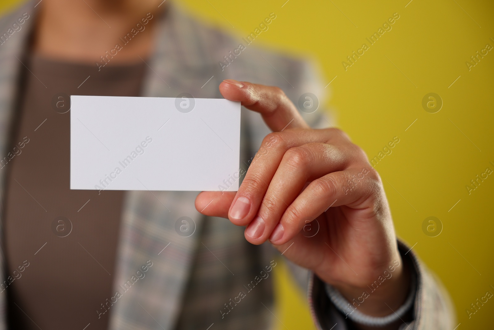 Photo of Woman holding blank business card on yellow background, closeup. Mockup for design