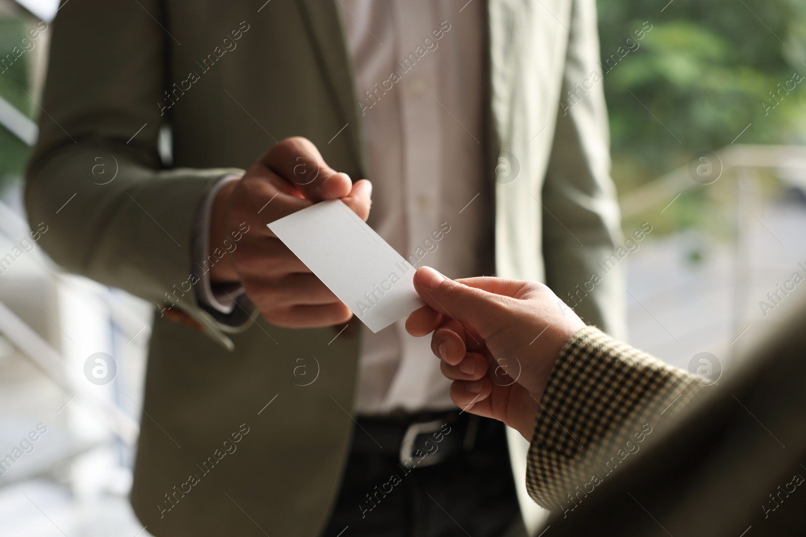 Photo of Man giving business card to woman in office, closeup. Mockup for design