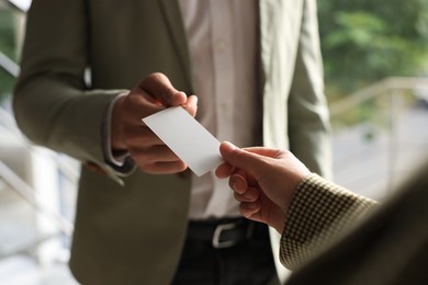 Man giving business card to woman in office, closeup. Mockup for design