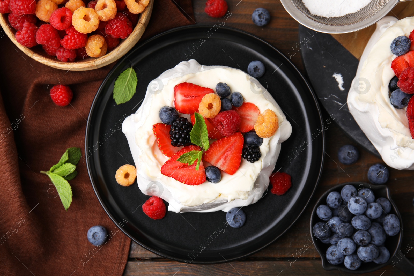 Photo of Pavlova cake (meringue dessert) with whipped cream, fresh berries and mint on wooden table, flat lay