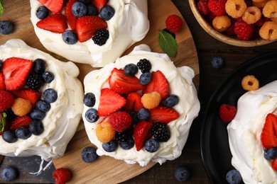 Photo of Pavlova cake (meringue dessert) with whipped cream and fresh berries on wooden table, flat lay