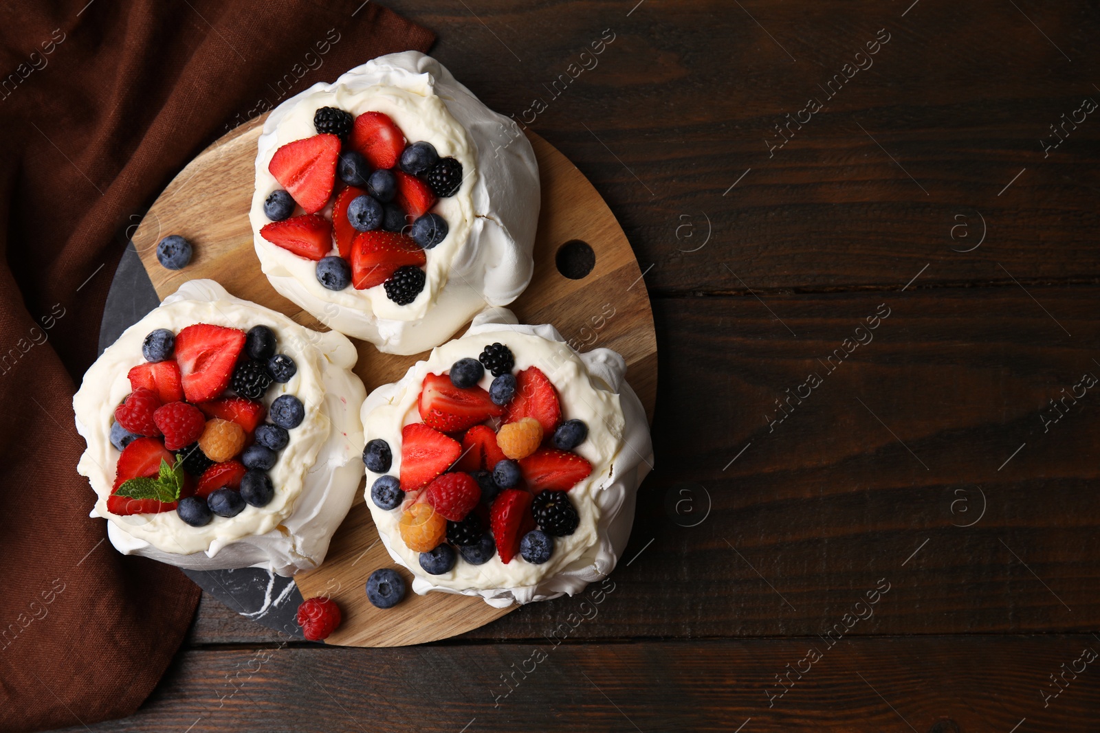 Photo of Pavlova cake (meringue dessert) with whipped cream and fresh berries on wooden table, top view. Space for text