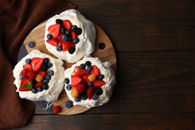 Photo of Pavlova cake (meringue dessert) with whipped cream and fresh berries on wooden table, top view. Space for text