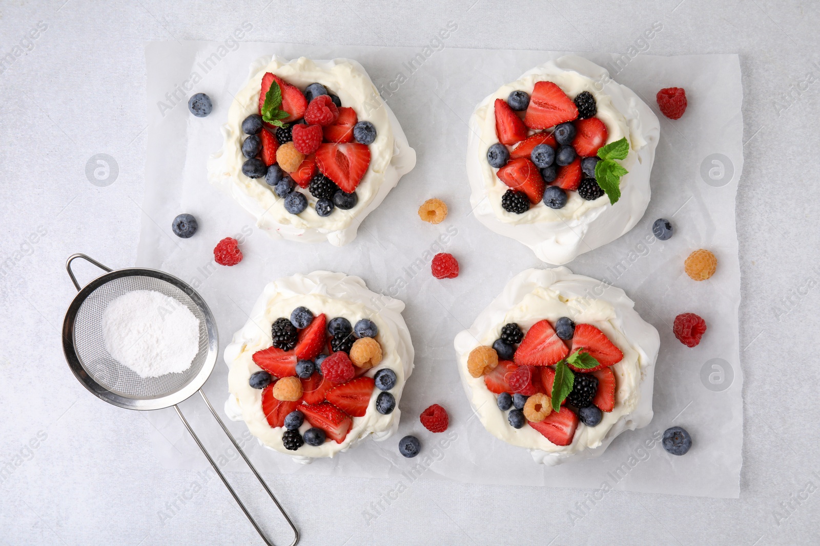 Photo of Pavlova cake (meringue dessert) with whipped cream and fresh berries on light grey table, flat lay