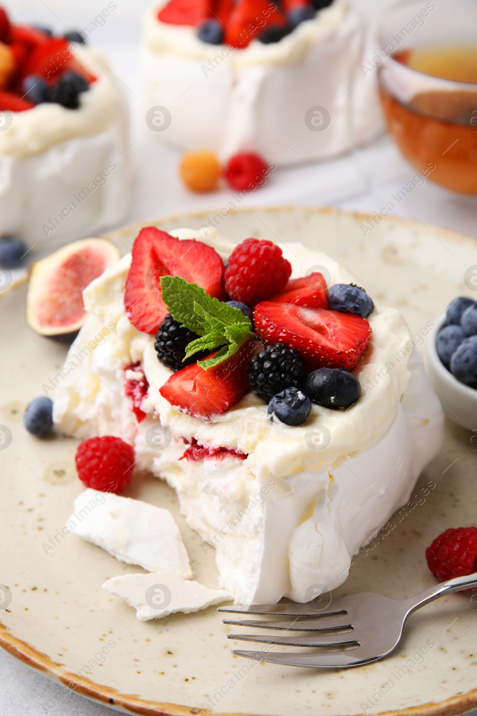 Photo of Pavlova cake (meringue dessert) with whipped cream, fresh berries, mint and fig on table, closeup