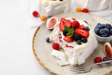 Photo of Pavlova cake (meringue dessert) with whipped cream, fresh berries, mint and fig on light table, closeup