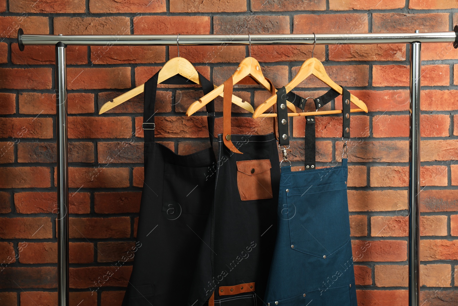 Photo of Many chef's aprons hanging on brick wall