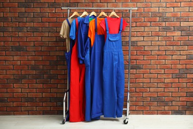 Photo of Different workers' uniforms on clothing rack near brick wall