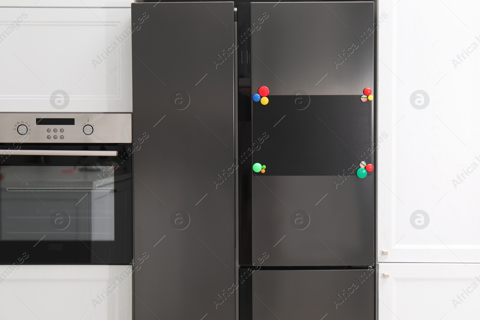 Photo of Blank note board with magnets on refrigerator in kitchen. Mockup for design