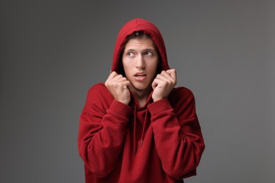 Portrait of scared young man on gray background