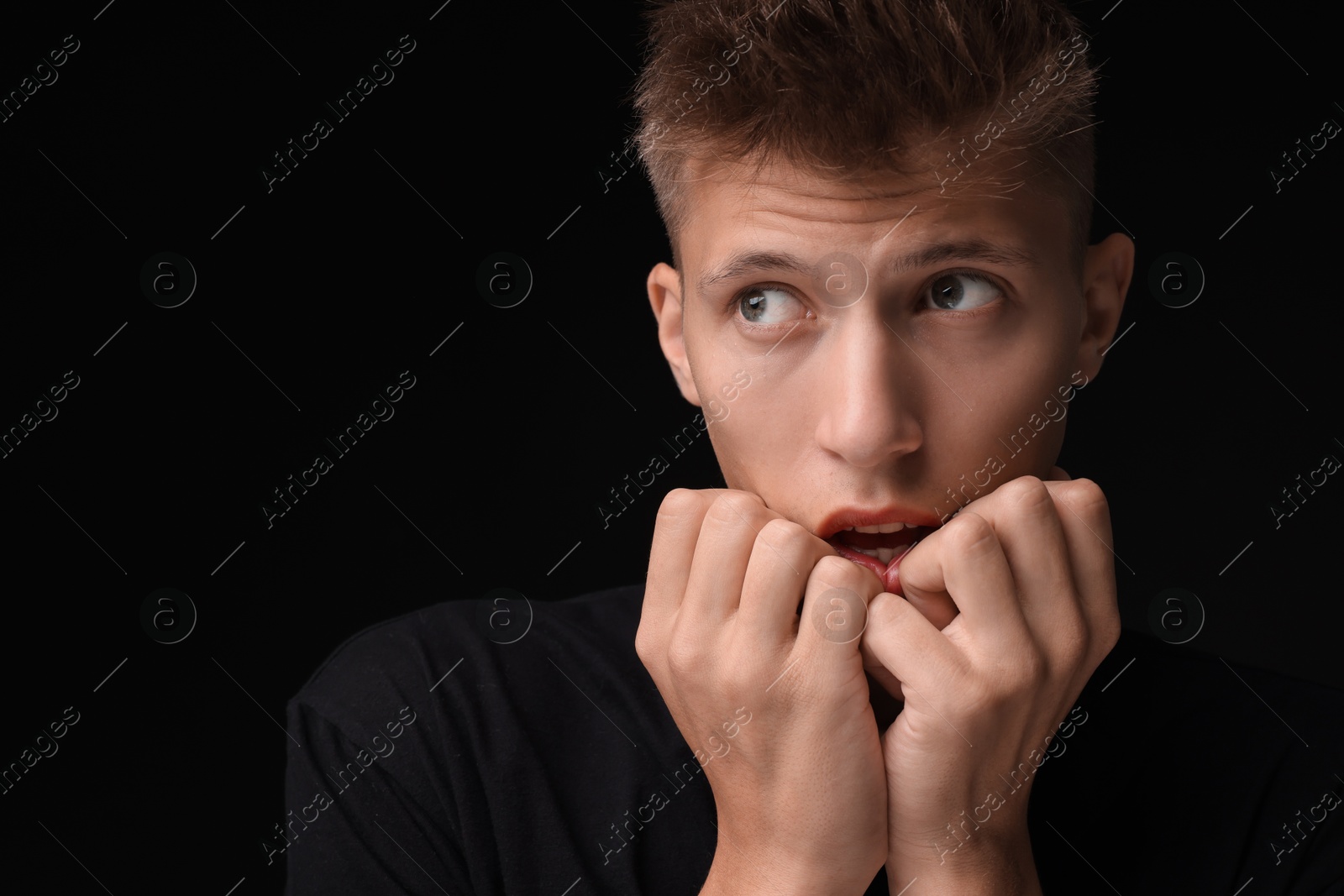 Photo of Portrait of scared young man on black background, space for text