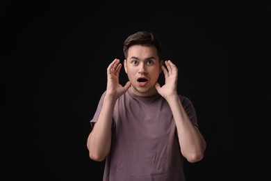 Photo of Portrait of scared young man on black background