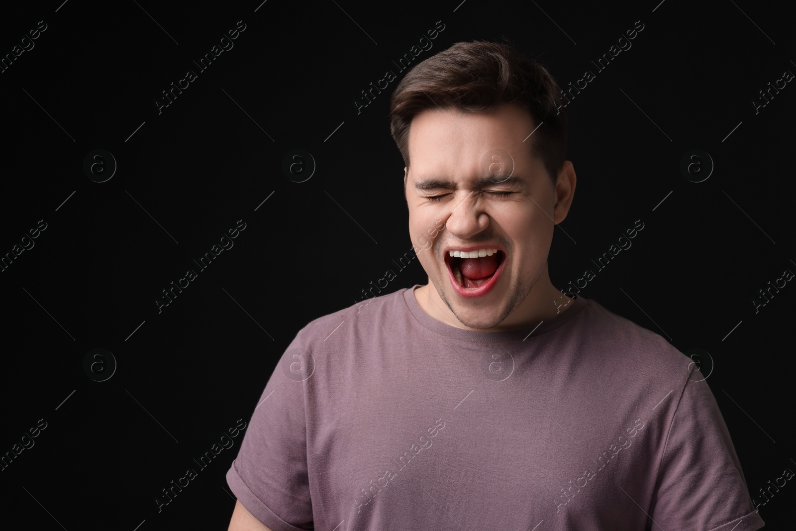 Photo of Portrait of scared young man on black background, space for text