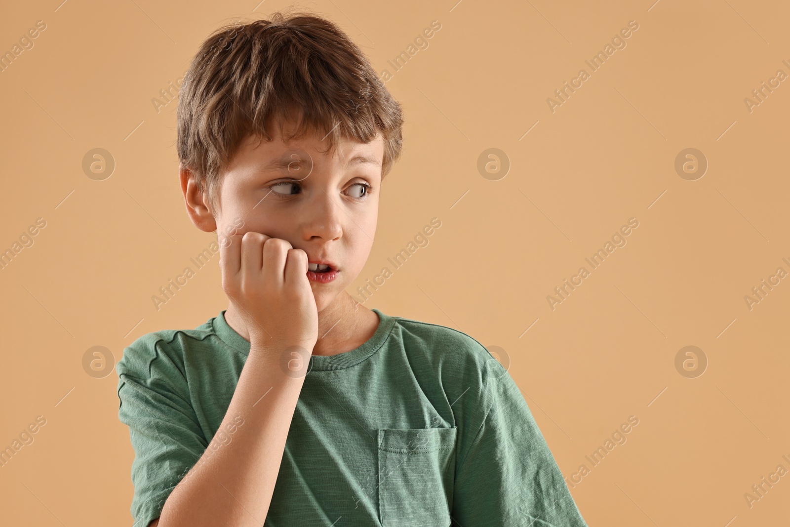 Photo of Scared little boy on beige background. Space for text