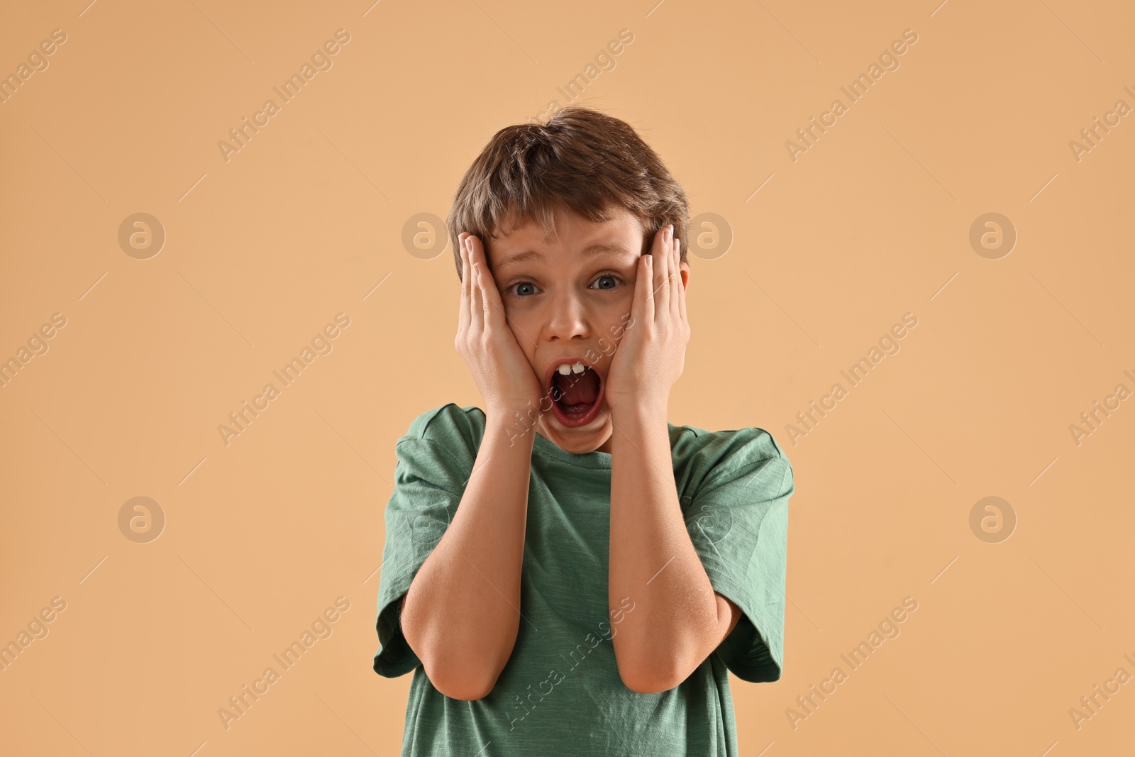 Photo of Scared little boy screaming on beige background