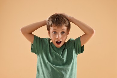 Portrait of scared little boy on beige background