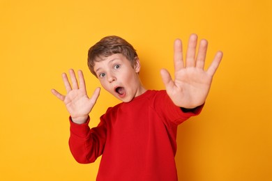 Photo of Portrait of scared little boy on orange background