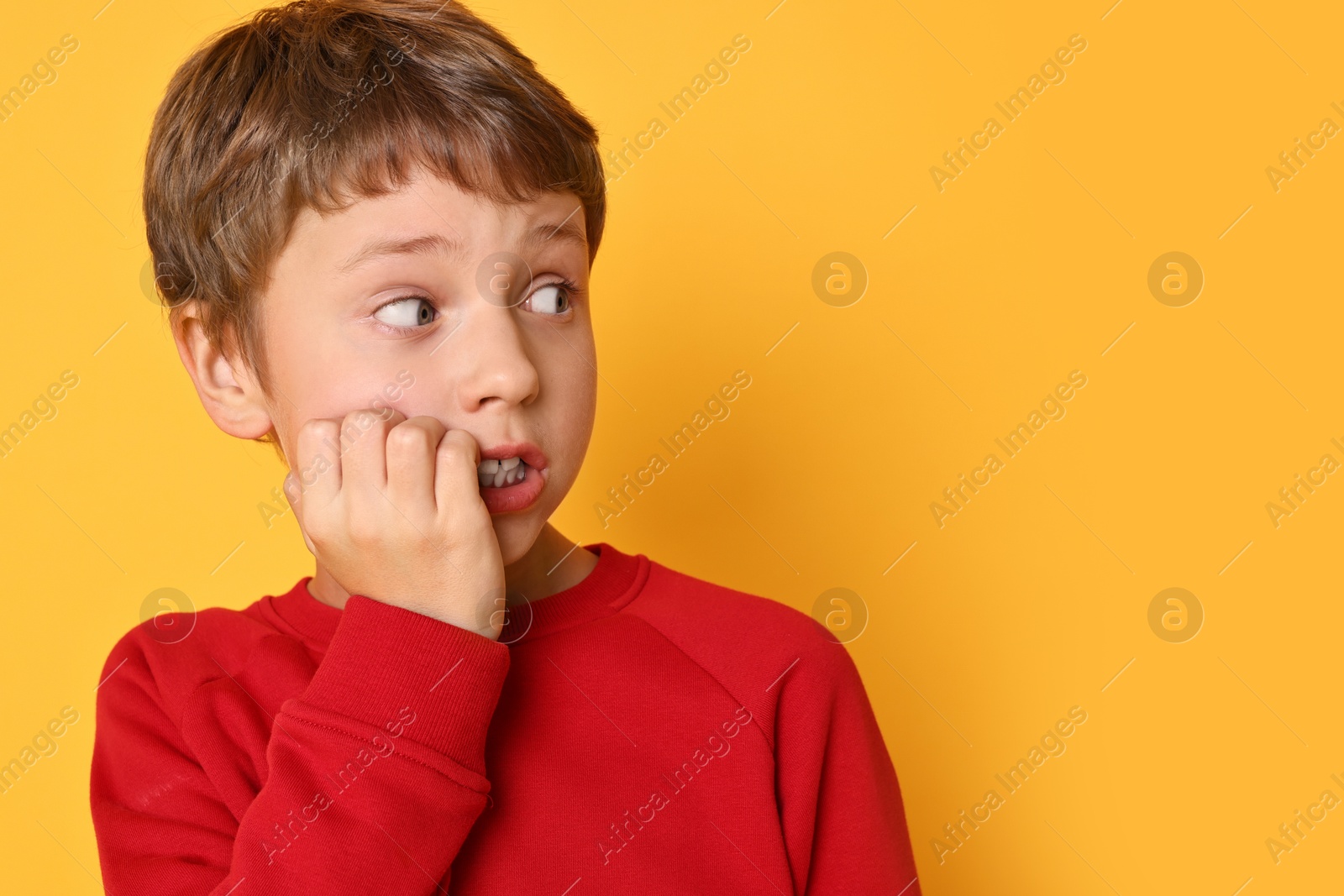 Photo of Scared little boy on orange background. Space for text