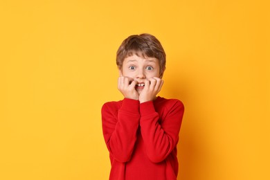 Portrait of scared little boy on orange background