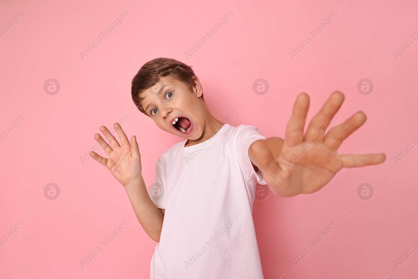 Photo of Portrait of scared little boy on pink background