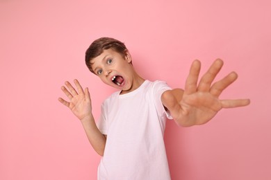 Portrait of scared little boy on pink background