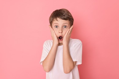 Portrait of scared little boy on pink background