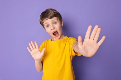 Portrait of scared little boy on violet background