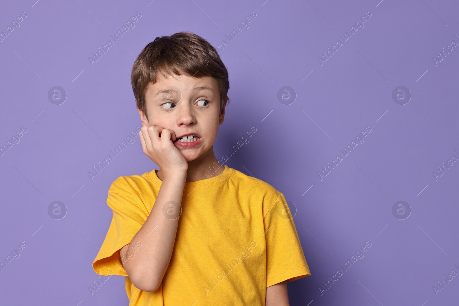 Photo of Portrait of scared little boy on violet background. Space for text