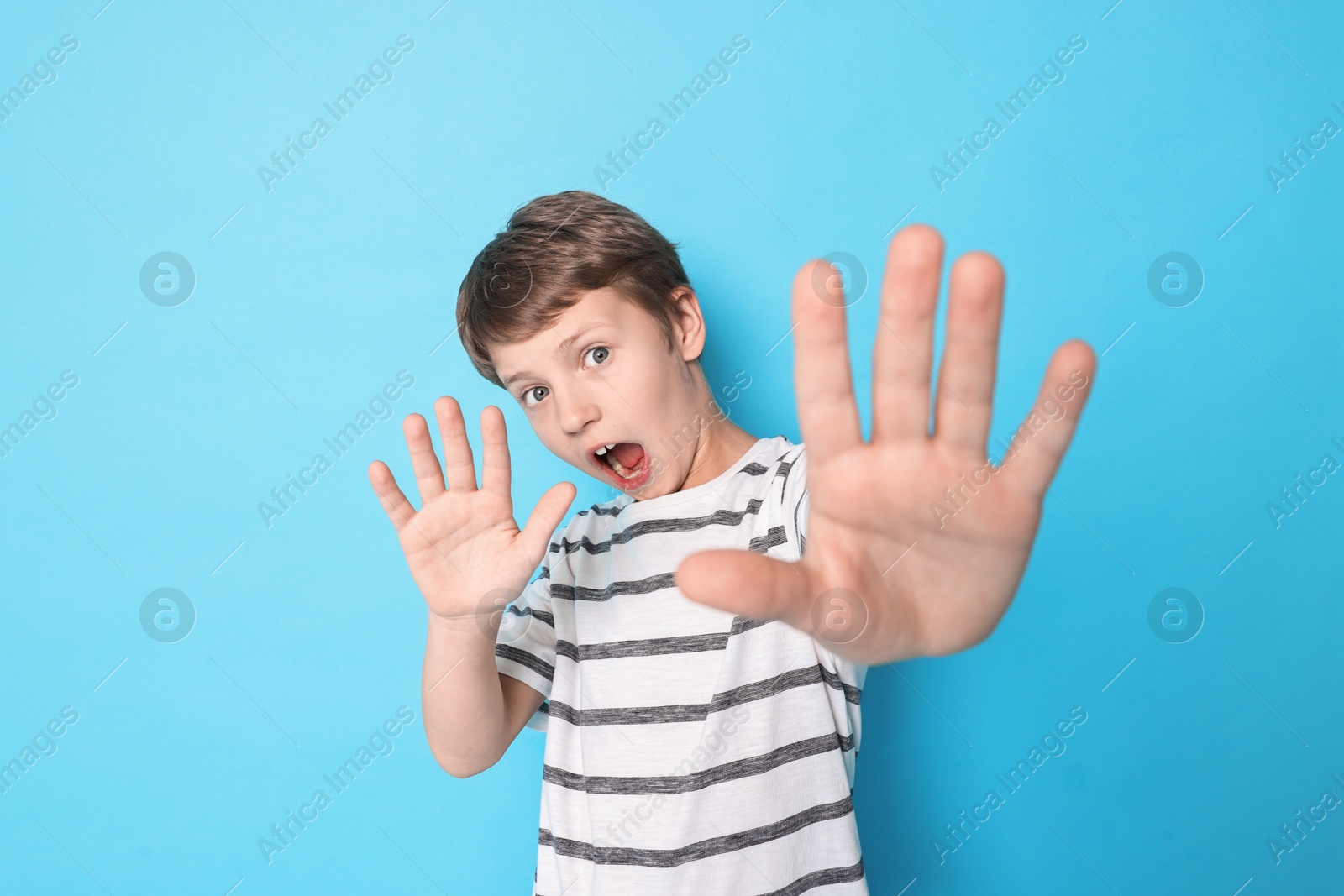 Photo of Scared little boy on light blue background