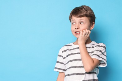 Photo of Scared little boy on light blue background. Space for text