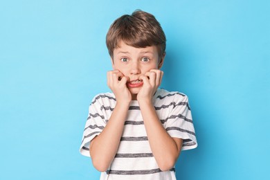 Photo of Scared little boy on light blue background