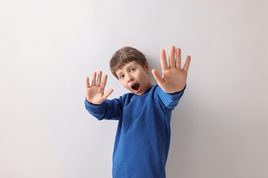 Portrait of scared little boy on light background